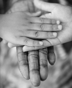 Black and white photo of two young hands resting on top of an older hand.